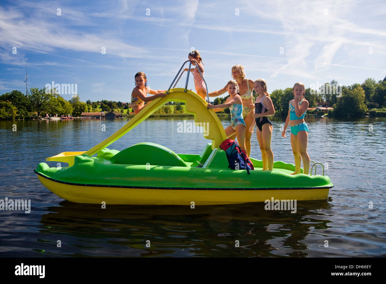 I bambini e le bambine, 8 anni, giocando su una barca a pedali con una slitta sul lago Staffelsee, Alta Baviera, Baviera Foto Stock