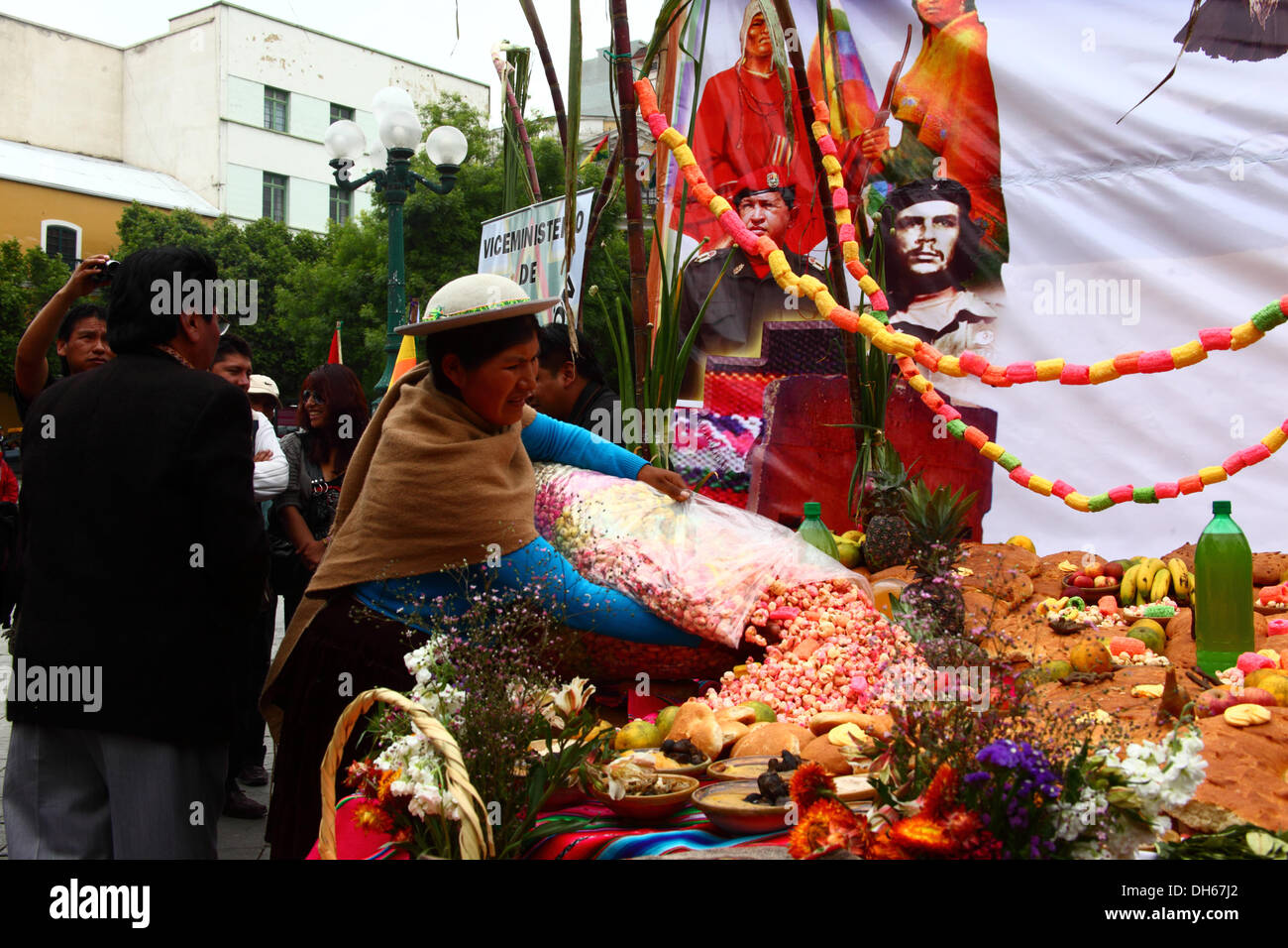 LA PAZ, BOLIVIA, 1 novembre 2013. Una signora riversa pasankalla (boliviano dolce fatto di mais tostato, un po' come popcorn) su un tipico altare (o mesa) che sono costruiti per ricevere le anime dei suoi cari per Todos Santos. La cerimonia è stata organizzata dal Ministero della decolonizzazione in onore delle popolazioni indigene e l'ala sinistra eroi, comprese Che Guevara e Hugo Chavez (entrambi raffigurata sul poster). Credito: James Brunker / Alamy Live News Foto Stock