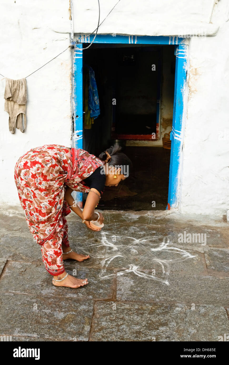 Le donne della pittura la terra davanti alla porta di entrata, Hampi, Karnataka, India, Asia Foto Stock