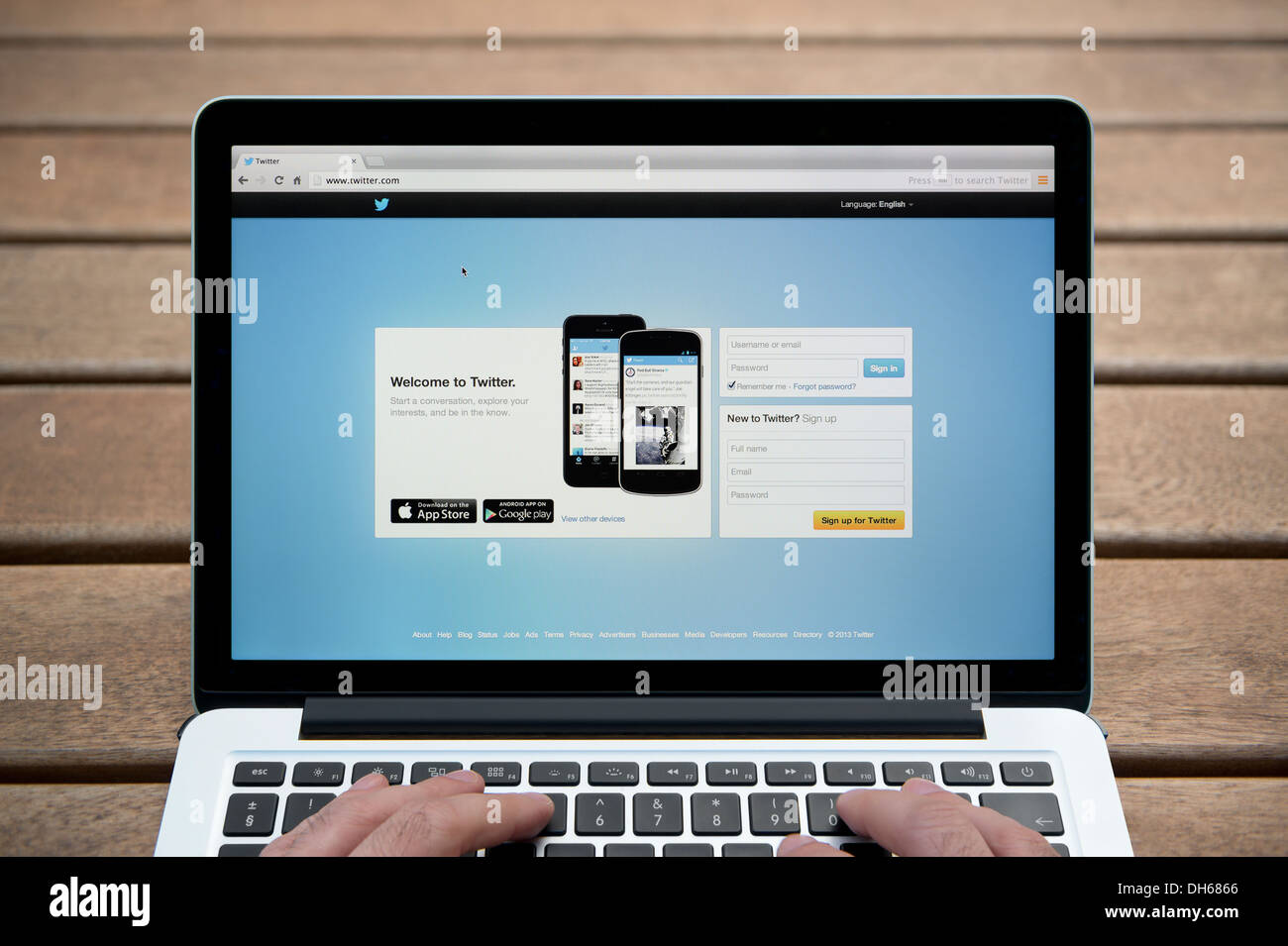 Il sito web di Twitter su un MacBook contro una panca in legno sfondo all'aperto tra cui un uomo le dita (solo uso editoriale). Foto Stock