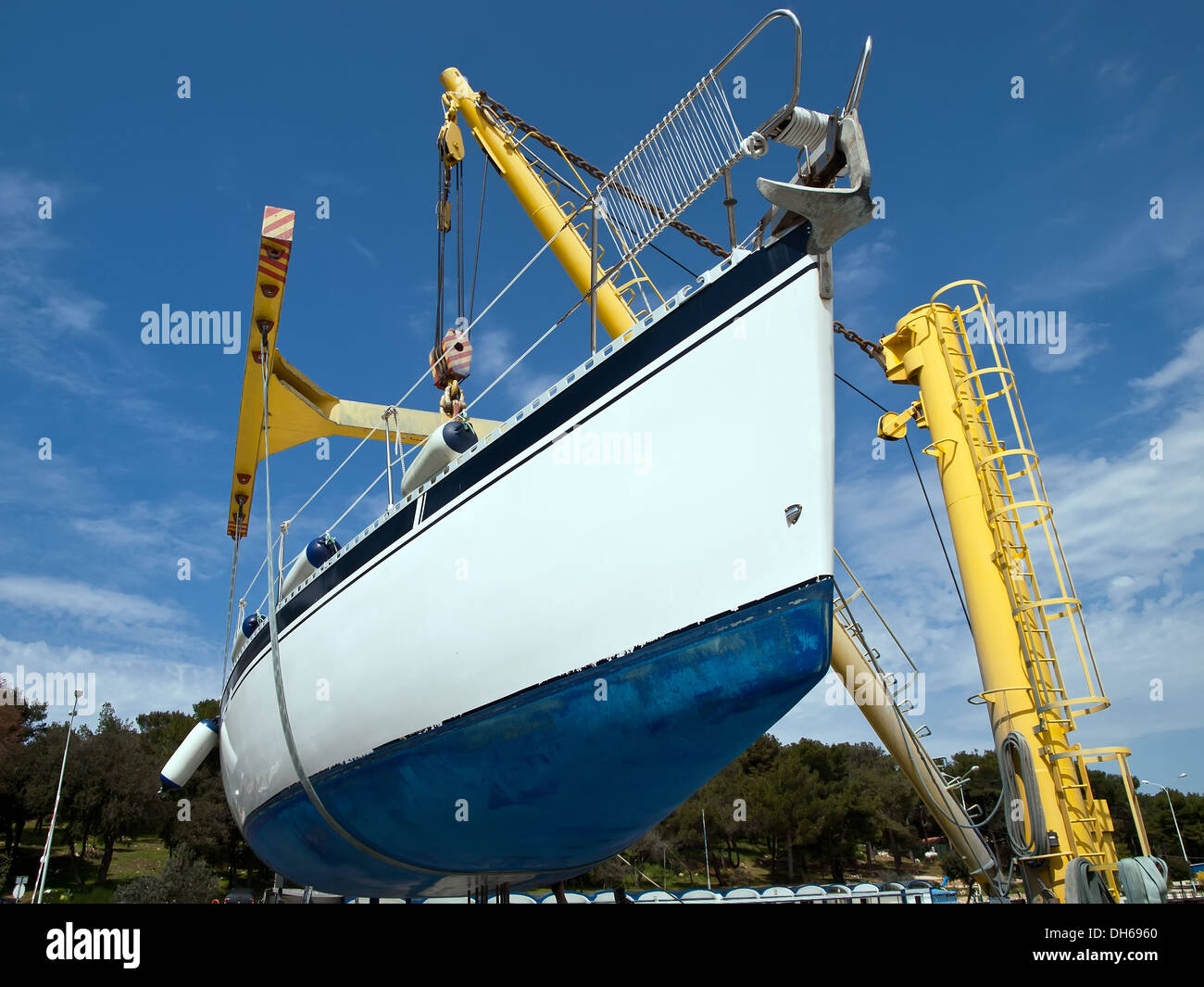 Barca a vela appeso alla gru di servizio del porto Foto Stock