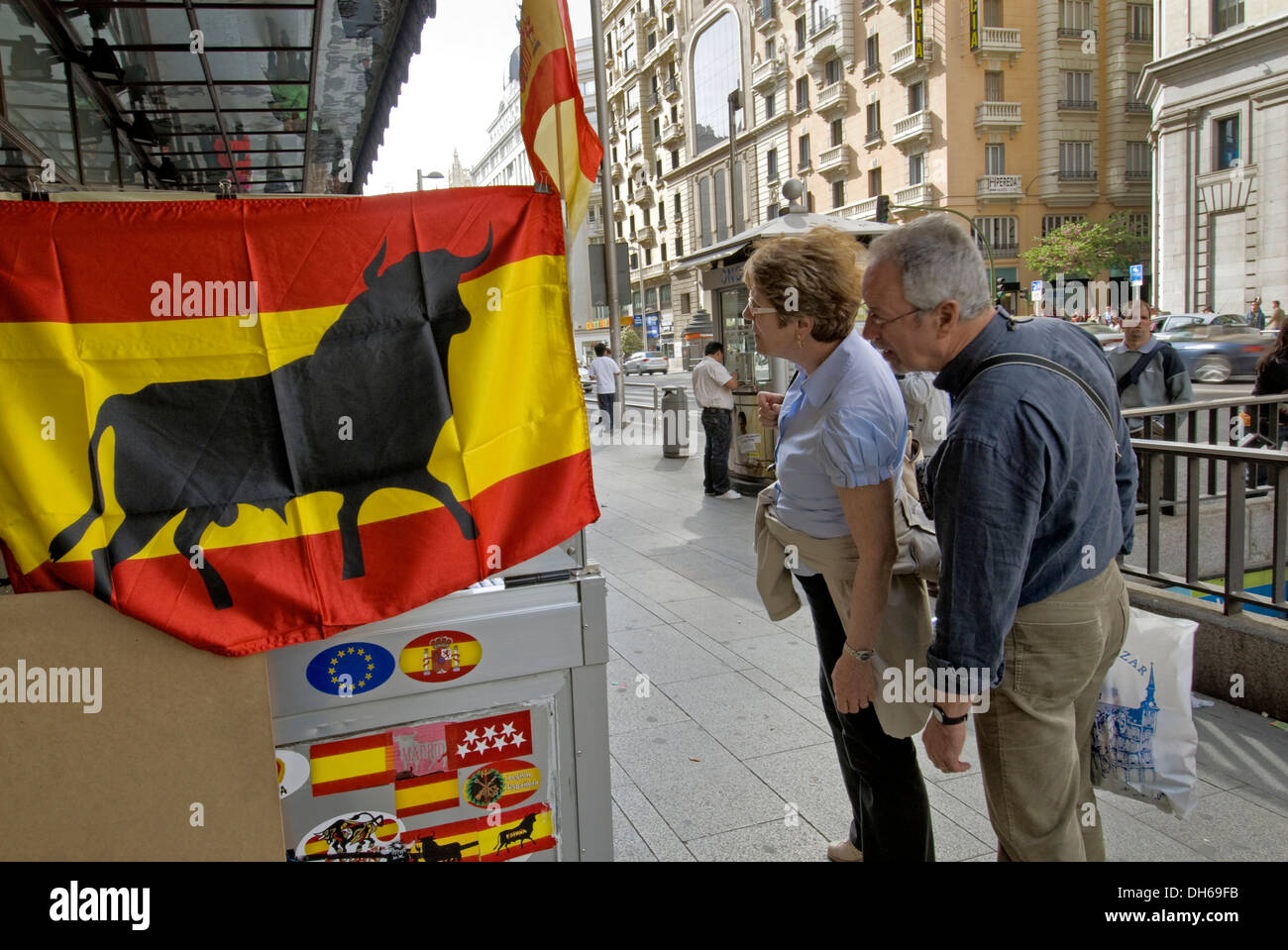 I turisti nella parte anteriore del negozio di souvenir con bandiera spagnola con Torro sulla Gran Via, Madrid, Spagna, Europa Foto Stock
