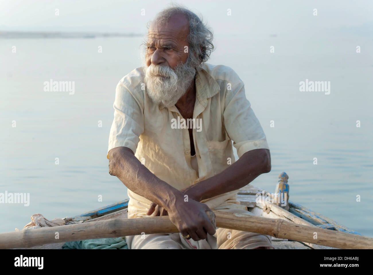 Il vecchio uomo remare una barca sul fiume Gange, Sunrise, Varanasi, India, Asia Foto Stock