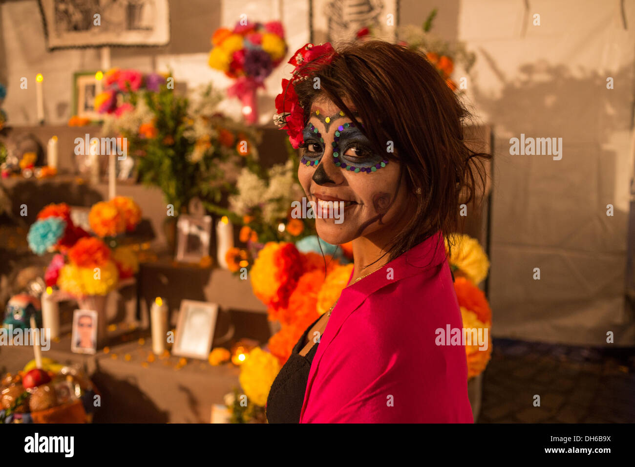 New York, NY, 31 ottobre 2013. Una donna in faccia la vernice si erge davanti al pubblico altare. La Dia de Muertos ha un lato stravagante. Foto Stock