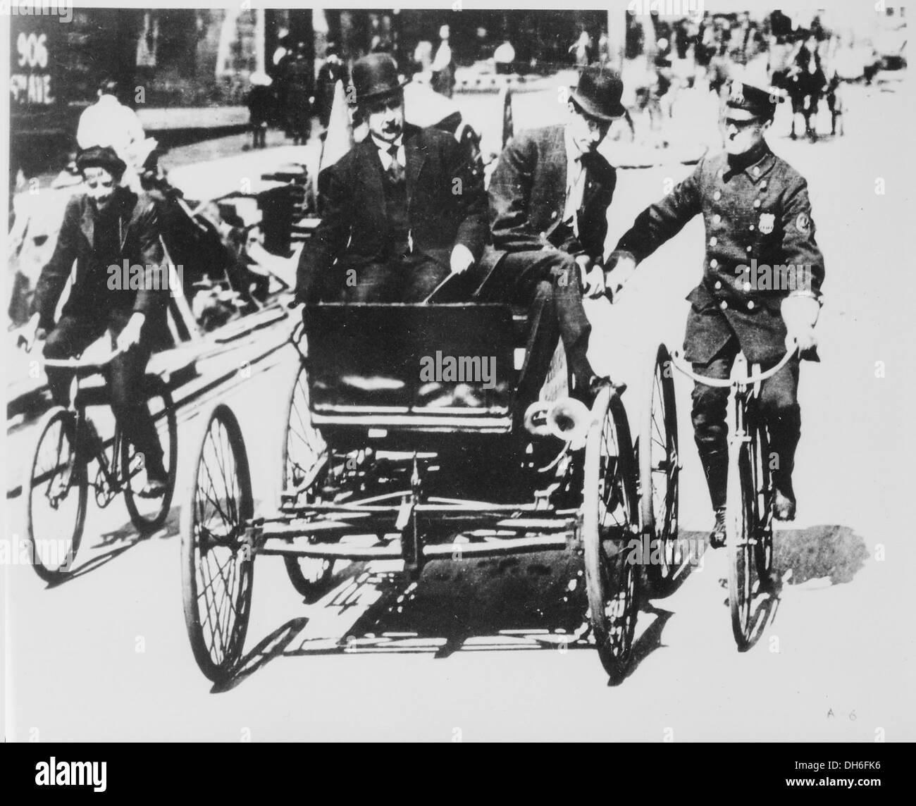 Nel 1949, un violatore alla guida di un'auto d'epoca del 1900 viene fermato da un poliziotto in bicicletta, catturando un momento di pratiche di polizia all'inizio del XX secolo nell'America urbana. Foto Stock