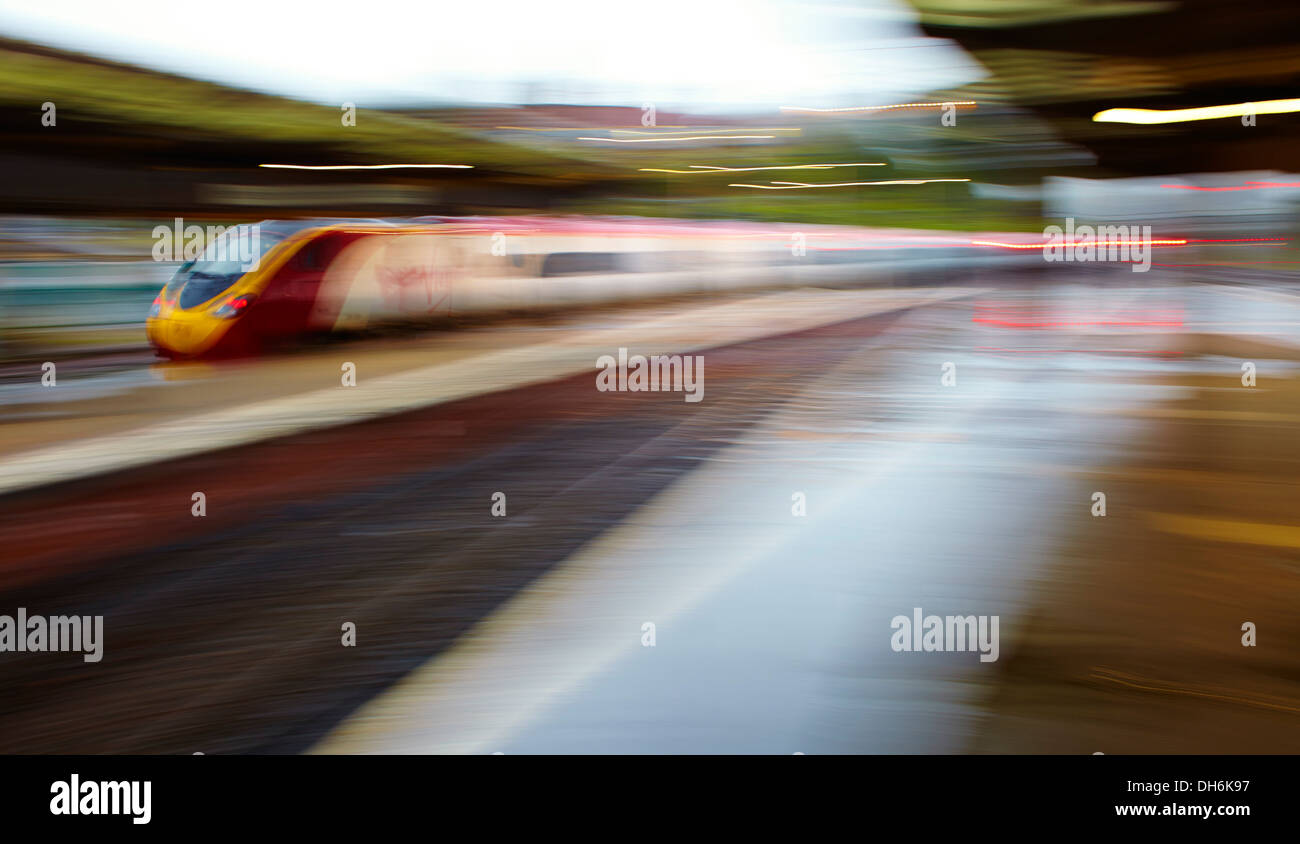 Vergine velocizzando il treno attraverso la stazione su westcoast mainline Foto Stock