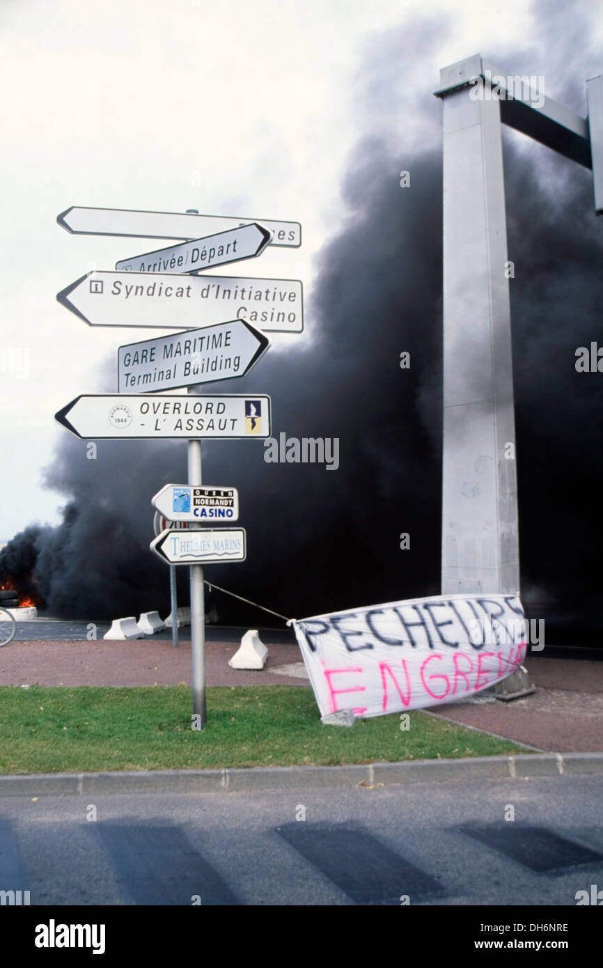 Denso fumo nero dalla combustione di pneumatici di un segnale di blocco del caen ouistreham porto dai pescatori francesi Foto Stock