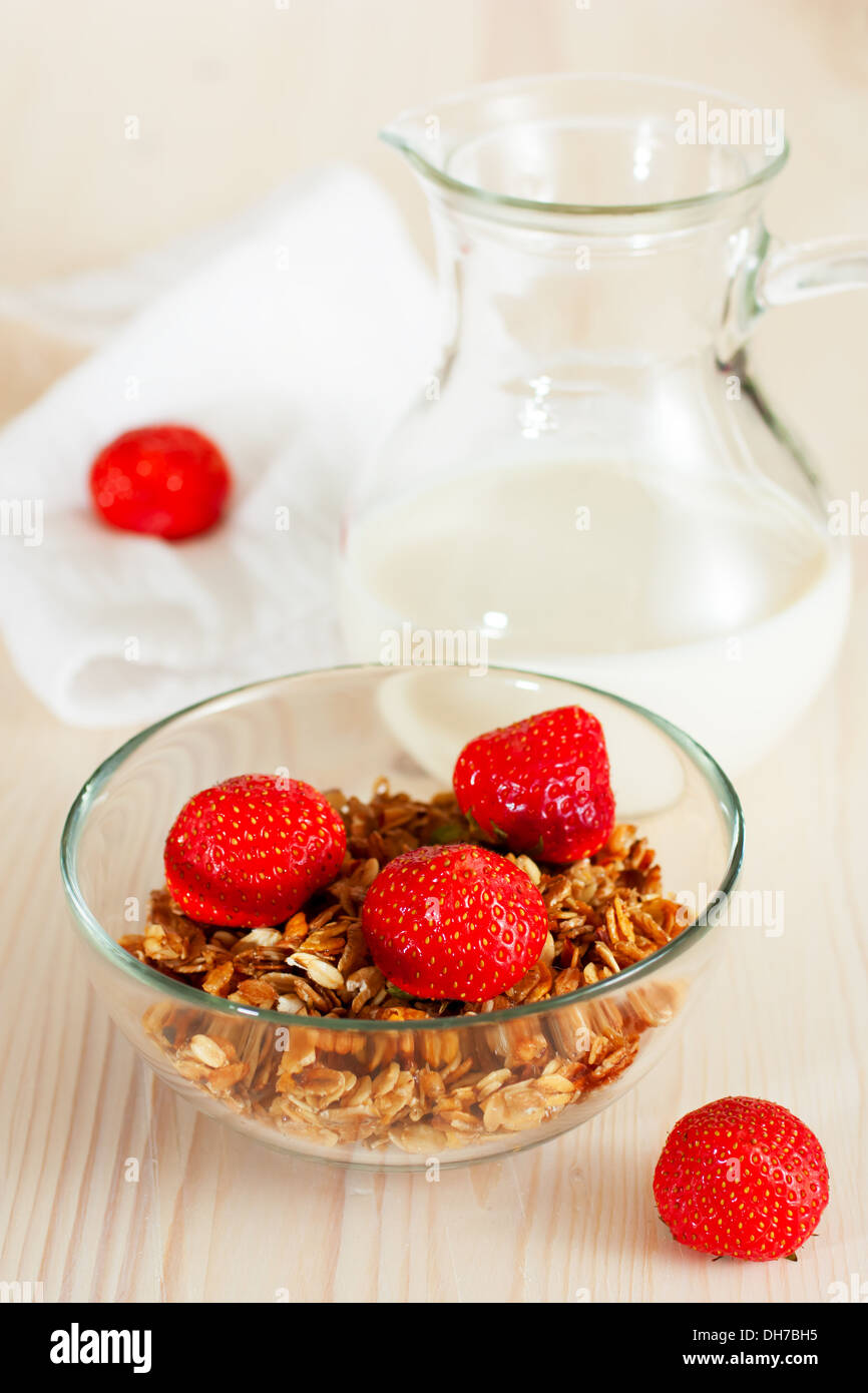 Muesli con latte e fragole, sullo sfondo di legno Foto Stock