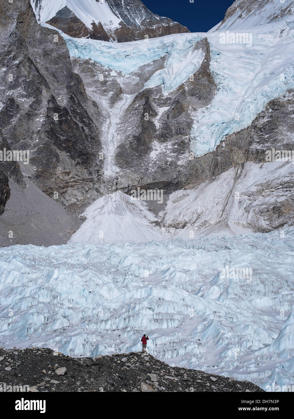 Un trekker in piedi di fronte ad un enorme ghiacciaio Khumbu vicino al Campo Base Everest in Nepal. Foto Stock