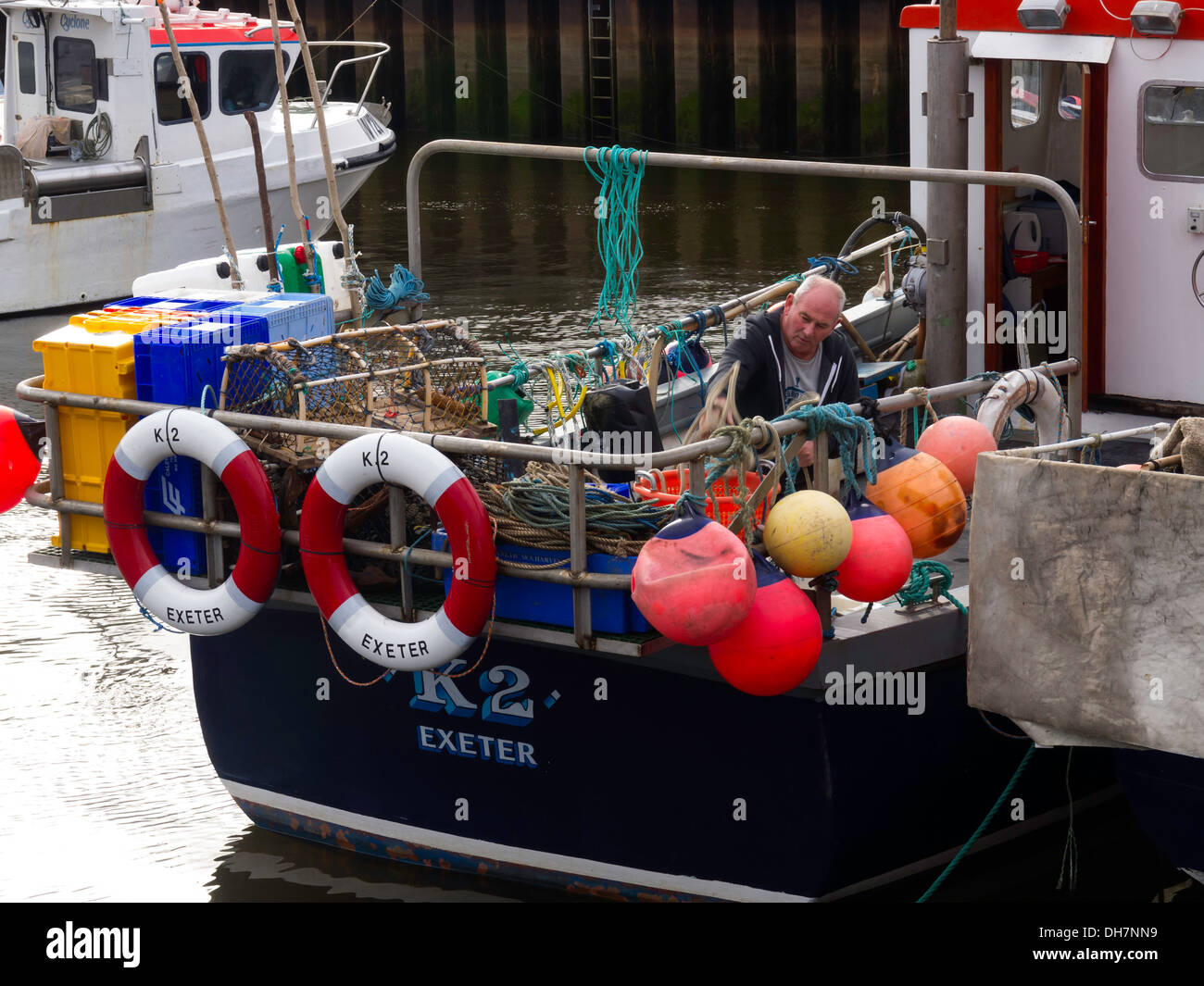 Un pescatore di riordino del granchio di attrezzature da pesca nella sua barca nel porto di Whitby. La barca "K2" Exeter un insolito visitatore a Whitby Foto Stock