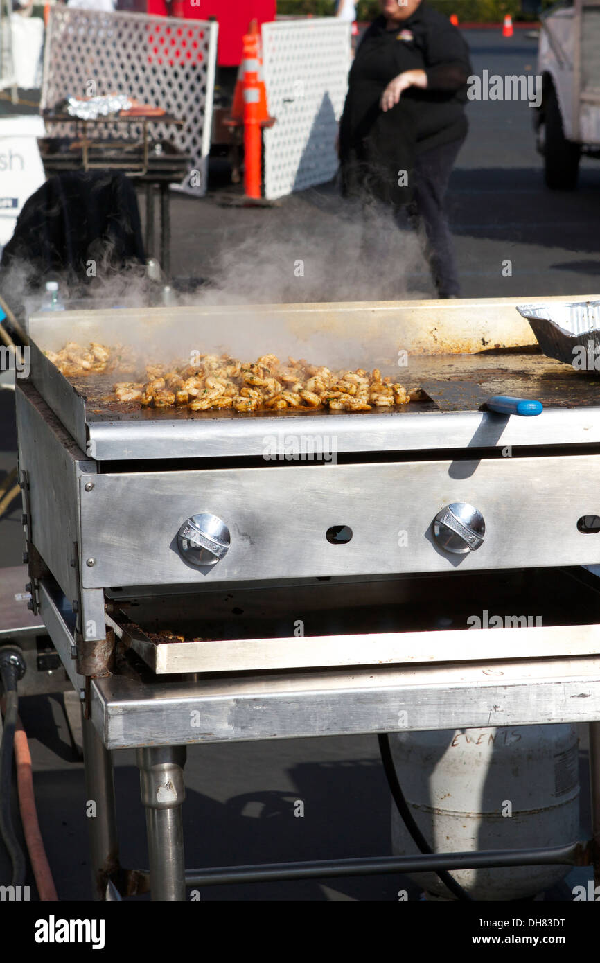 Pollo alla griglia la cottura al di fuori su un grill a gas in corrispondenza di un evento esterno Foto Stock