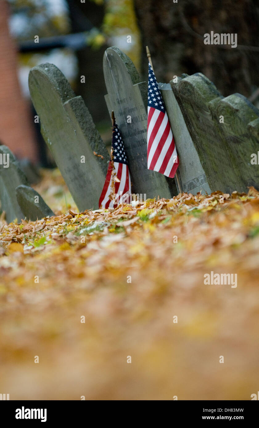 Bandierine americane adornano le lapidi di veterani di guerra in una rivoluzionaria era il cimitero di Boston, Massachusetts, in autunno. Foto Stock