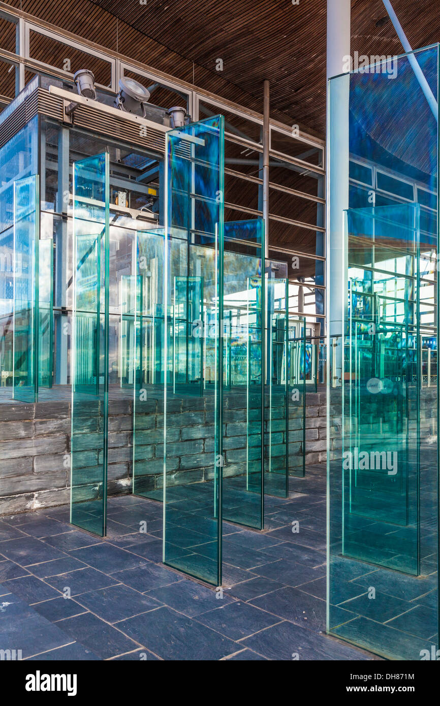 Il campo di gruppo al di fuori del Senedd nella Baia di Cardiff Galles. Moderni pannelli di vetro formano una pausa di vento sia funzionale e artistica. Foto Stock