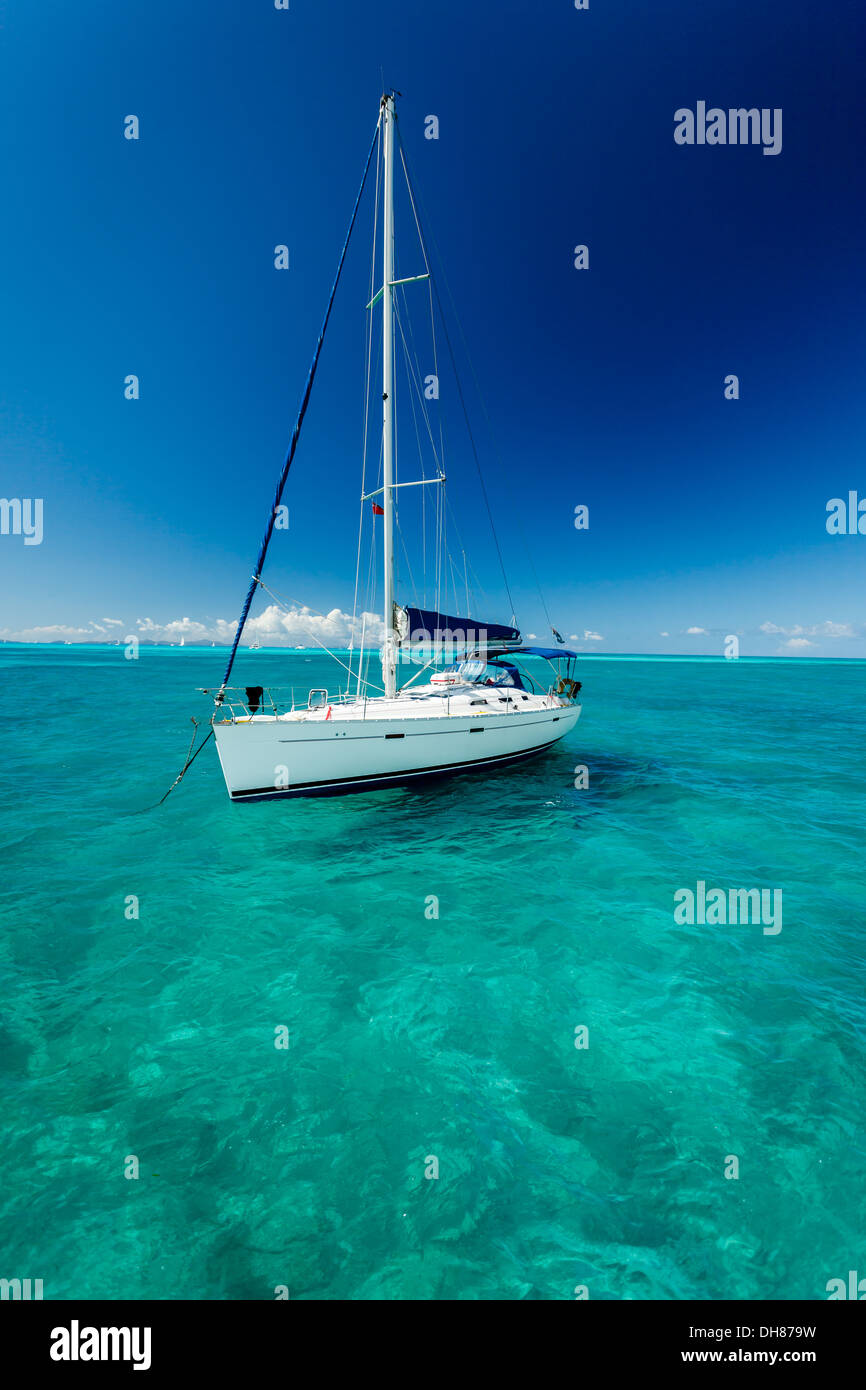 Barca a vela bianca galleggia sul chiaro blu turchesi acque dei Caraibi come se sospeso su trasparente ripiano in vetro Foto Stock