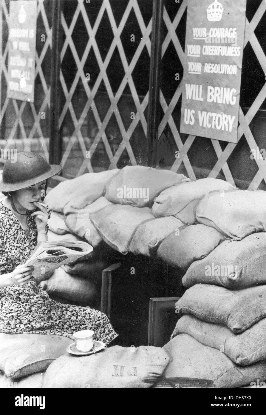 Una giovane donna siede sui sacchi di sabbia al di fuori del suo ufficio di Londra durante il blitz Foto Stock