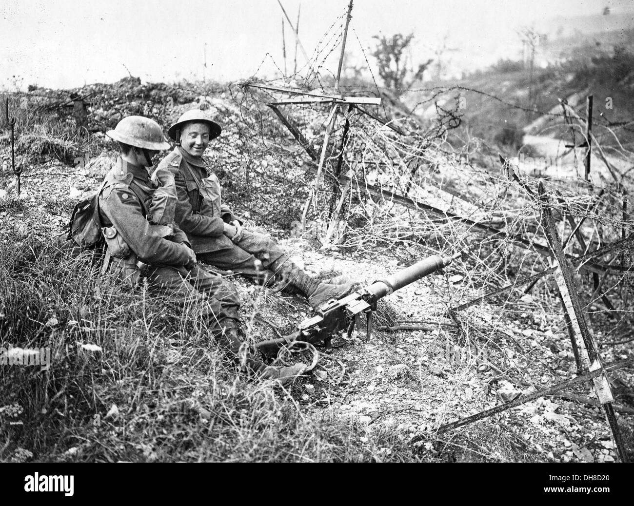 Grande Guerra una guerra di trincea. Soldati britannici di sedersi su un catturato la posizione tedesca tra il filo spinato aggrovigliamenti e scartato gun Foto Stock
