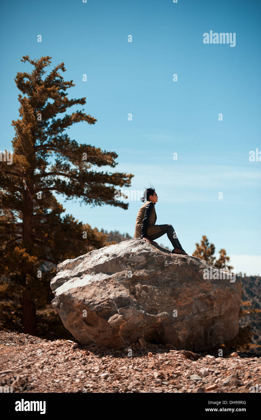 Donna seduta su una roccia in Angeles National Forest vicino a Los Angeles, CA. Foto Stock