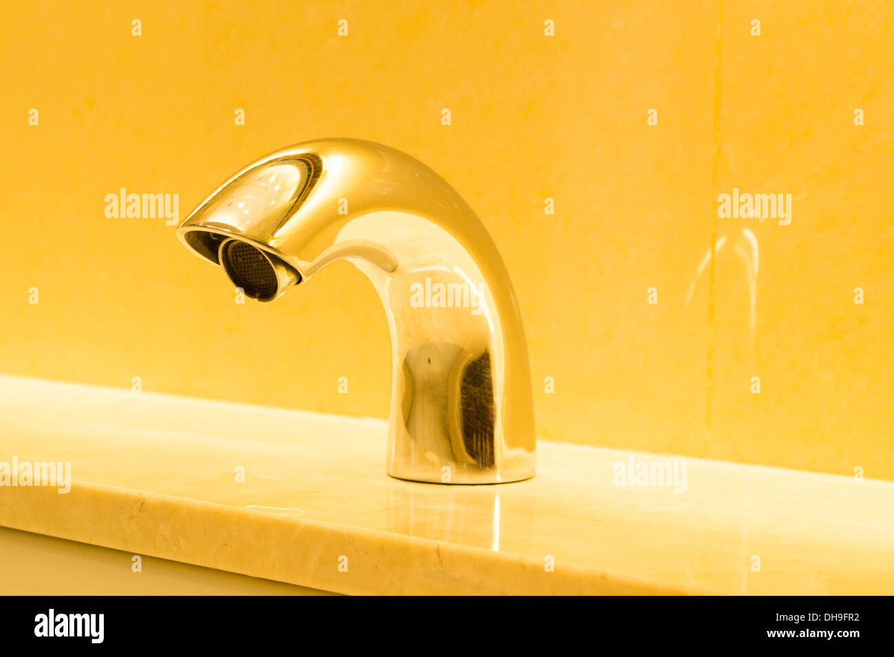 Lavandino in marmo con rubinetto luce dorata Foto Stock