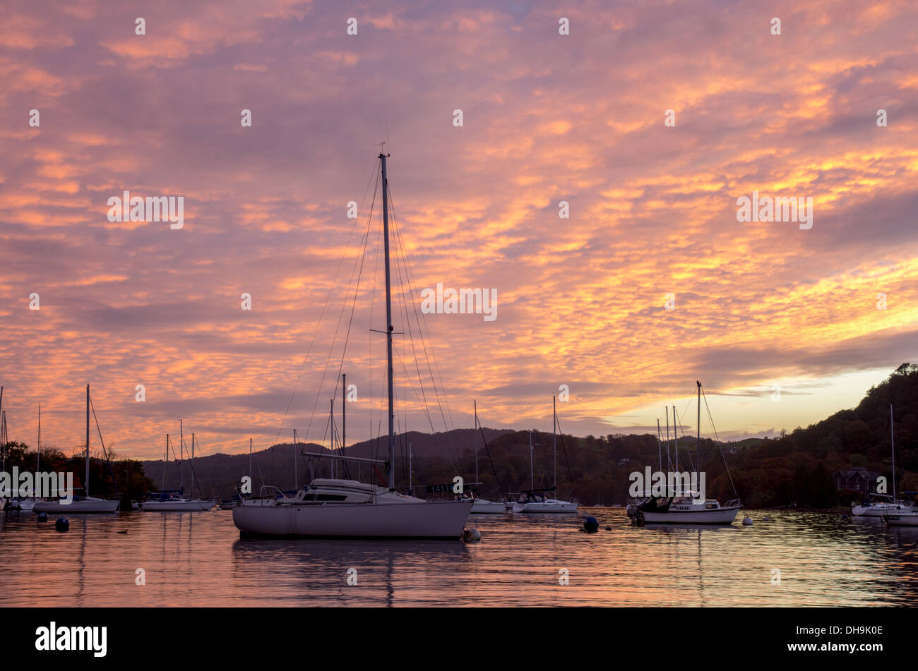 Un incredibile tramonto colorato scena su Windermere nel Lake District. bella arancione e rosa di colori tra le nuvole. Foto Stock