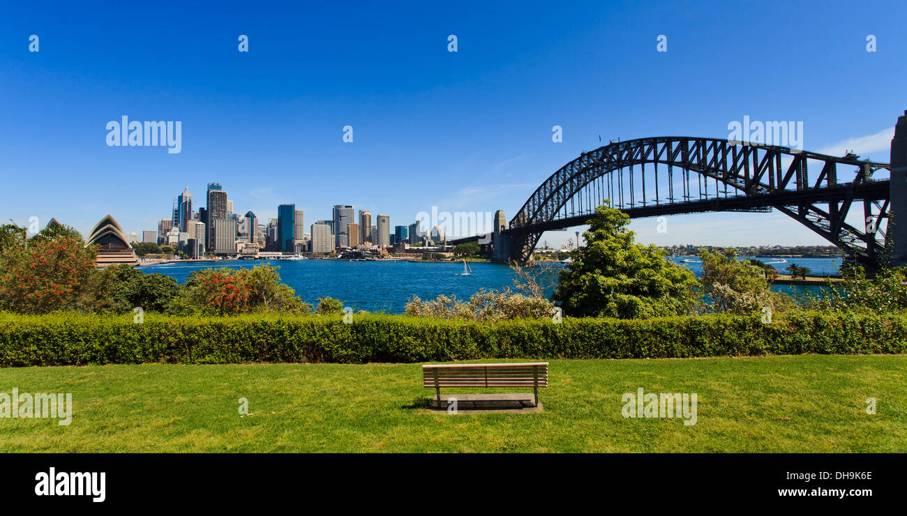Vista panoramica della città di Sydney CBD e Harbour Bridge i punti di riferimento dal parco verde con banco di erba e blossom tree estate giornata di sole Foto Stock