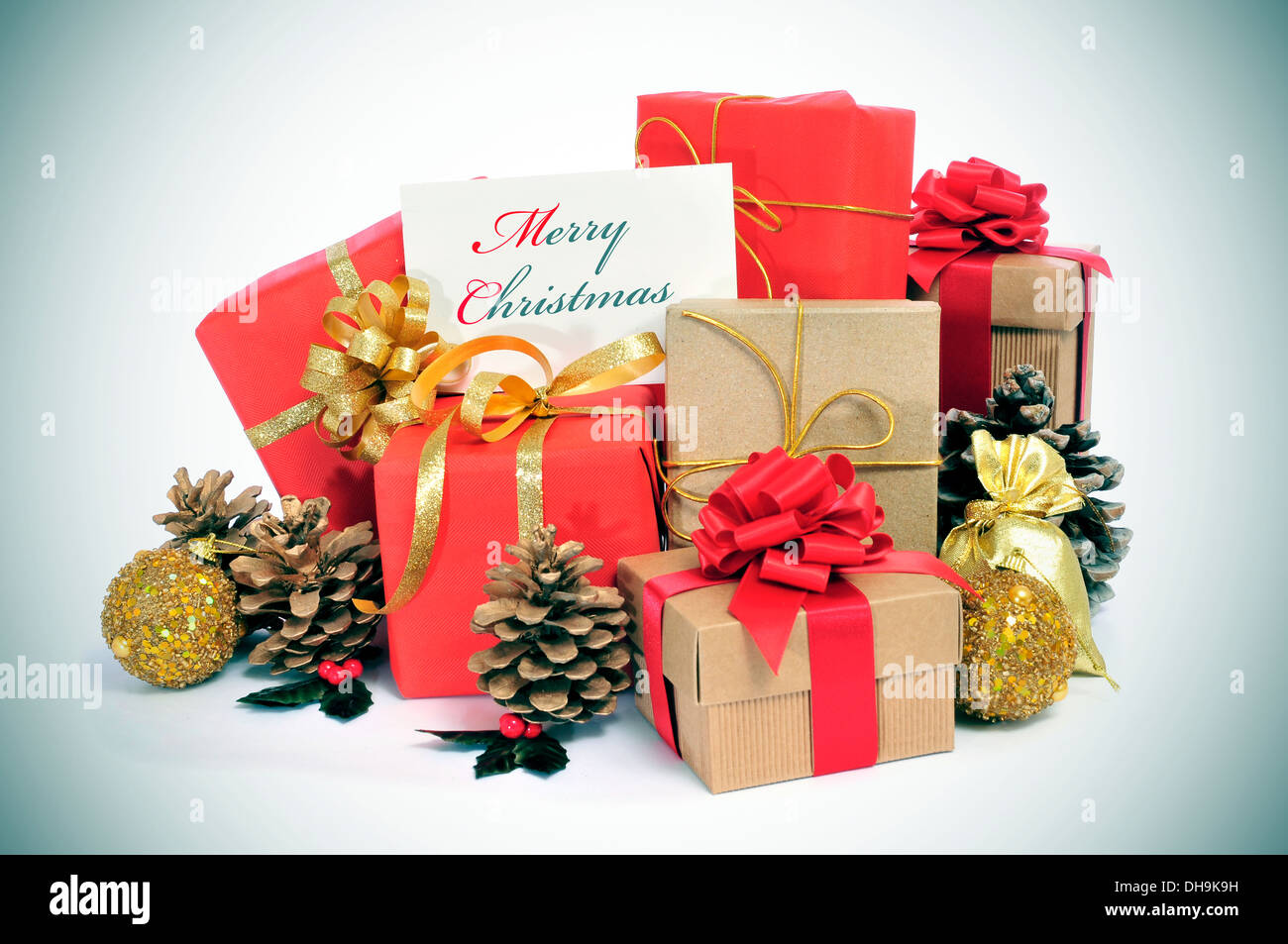 Alcuni regali di Natale avvolto con della carta da imballaggio di diversi colori e nastro di archi, e alcuni ornamenti natale e un signbo Foto Stock