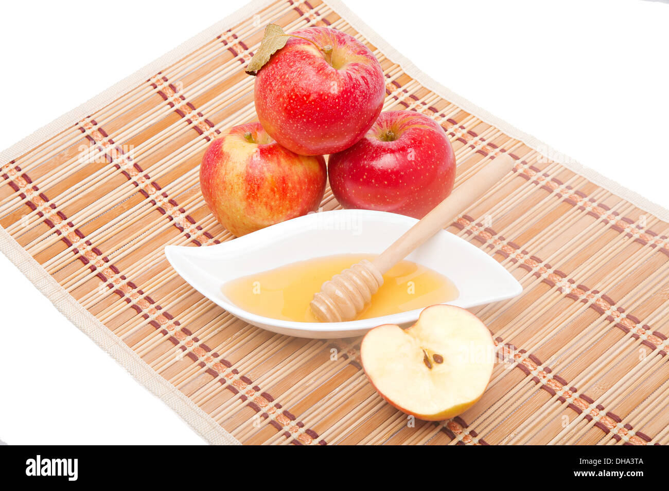 Fette di mela e miele il bilanciere con tre mele rosse sulla stuoia di paglia Foto Stock