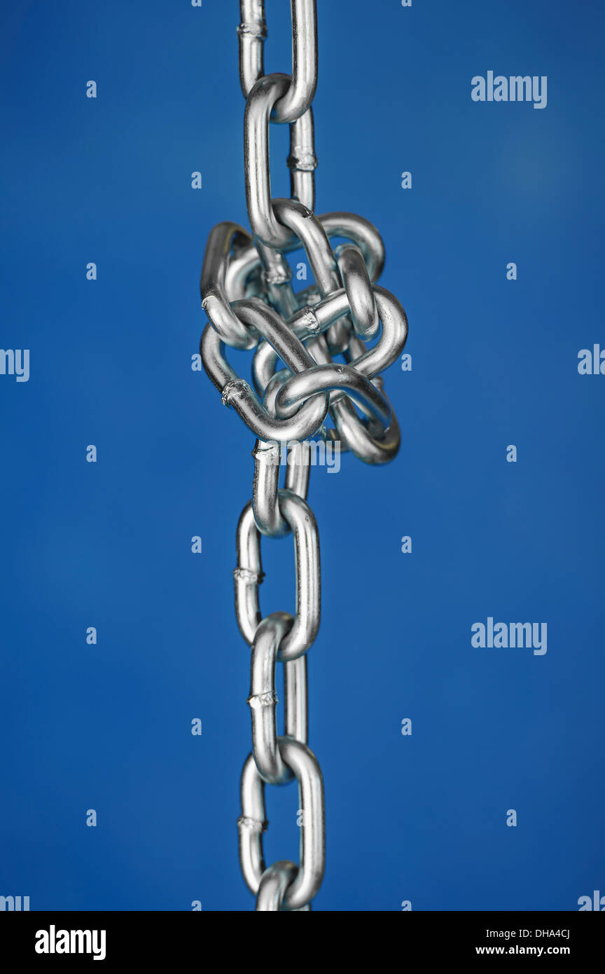Una catena legati in un nodo contro uno sfondo blu Foto Stock