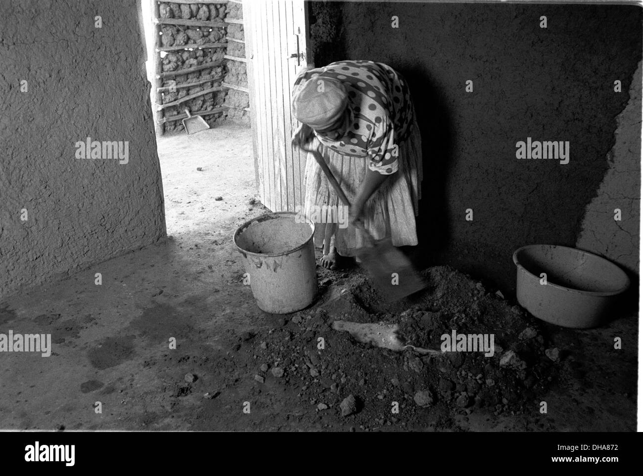 Ipjr09090230la povertà e la dignità. Giugno 2004. Ms Mzila aggiunge acqua all'argilla a secco per la preparazione di un intonaco da applicare alle pareti.. Ms Foto Stock