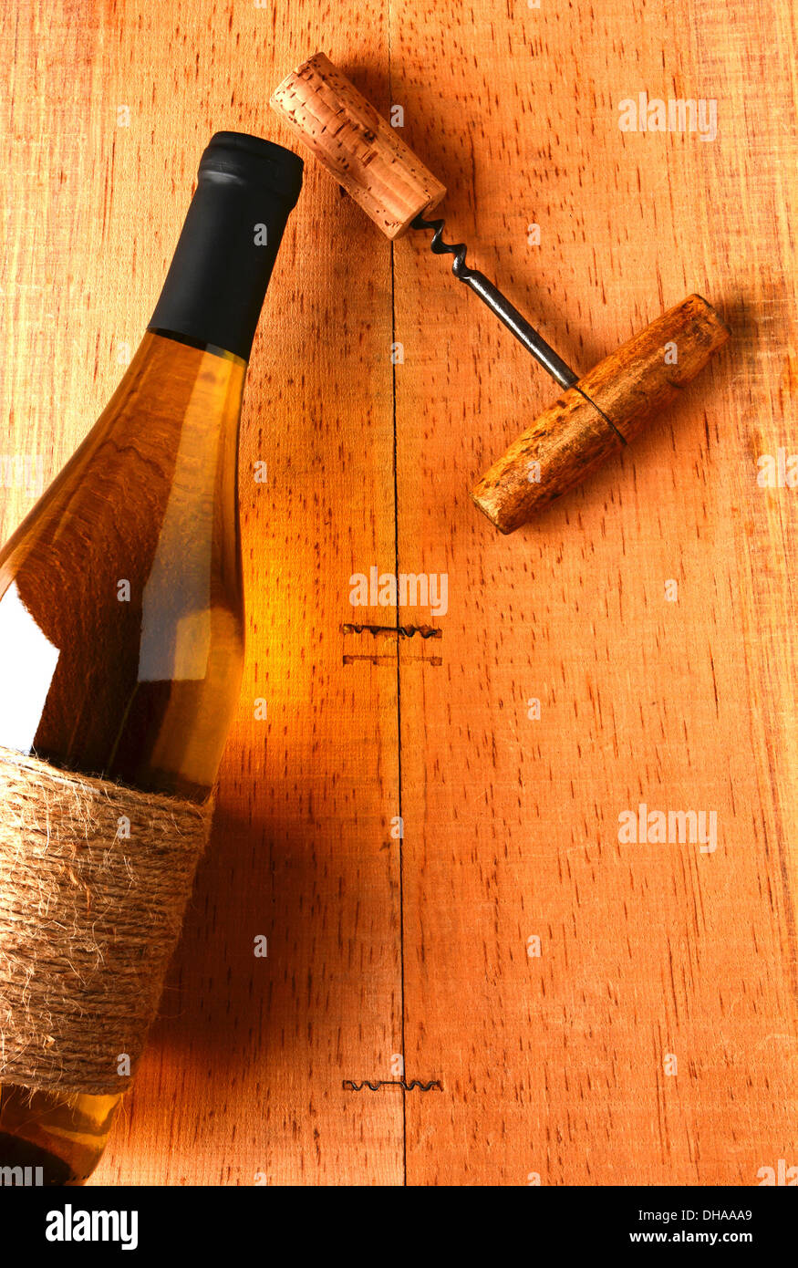 Uno chardonnay bottiglia di vino e un cavatappi su un rustico di superficie di legno. Vista dal di sopra della bottiglia è parzialmente al di fuori del telaio Foto Stock