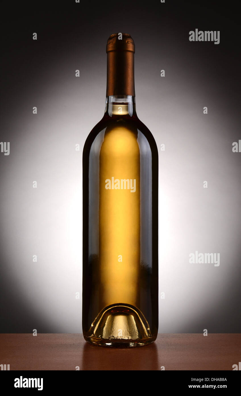 Primo piano di un vino bianco bottiglia retroilluminato con una luce a sfondo grigio scuro. Formato verticale. Foto Stock