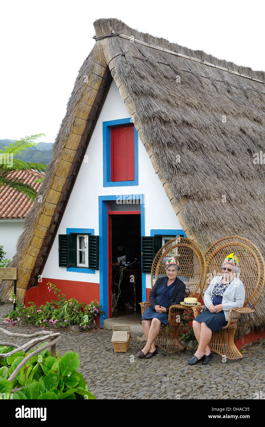Madeira Portogallo. Due donne anziane rappresentano per avere le loro foto scattata nella parte anteriore di un tradizionale Palheiro un telaio house di Santana Foto Stock