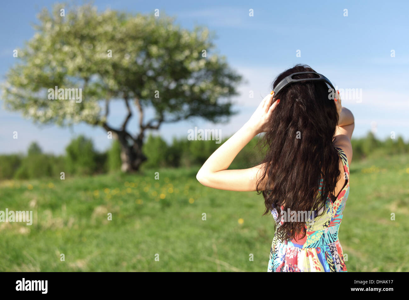 Giovane donna con le cuffie per ascoltare musica sul campo Foto Stock