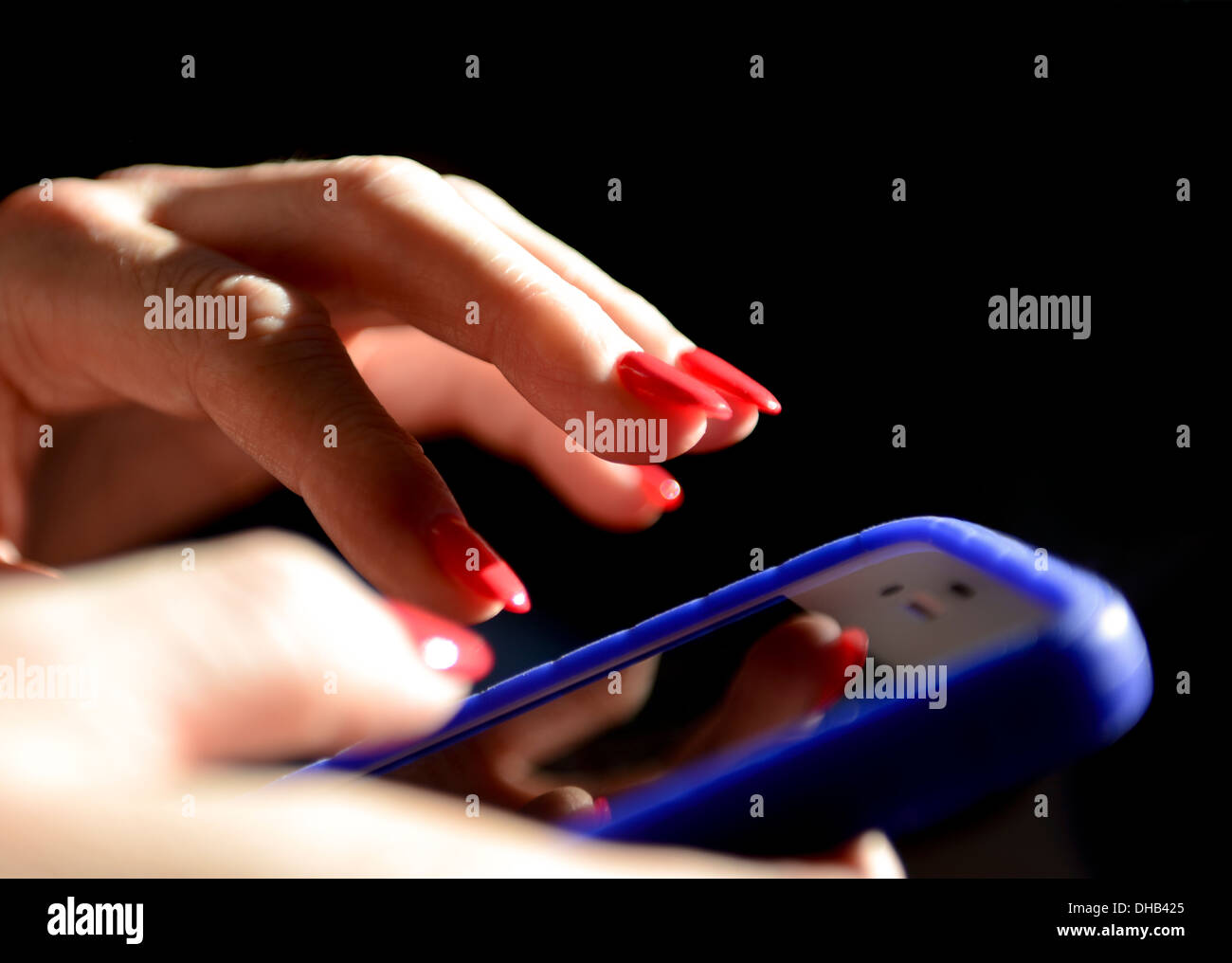 Un womans mani vicino con dipinta di rosso le unghie delle dita in possesso di una smart phone Foto Stock