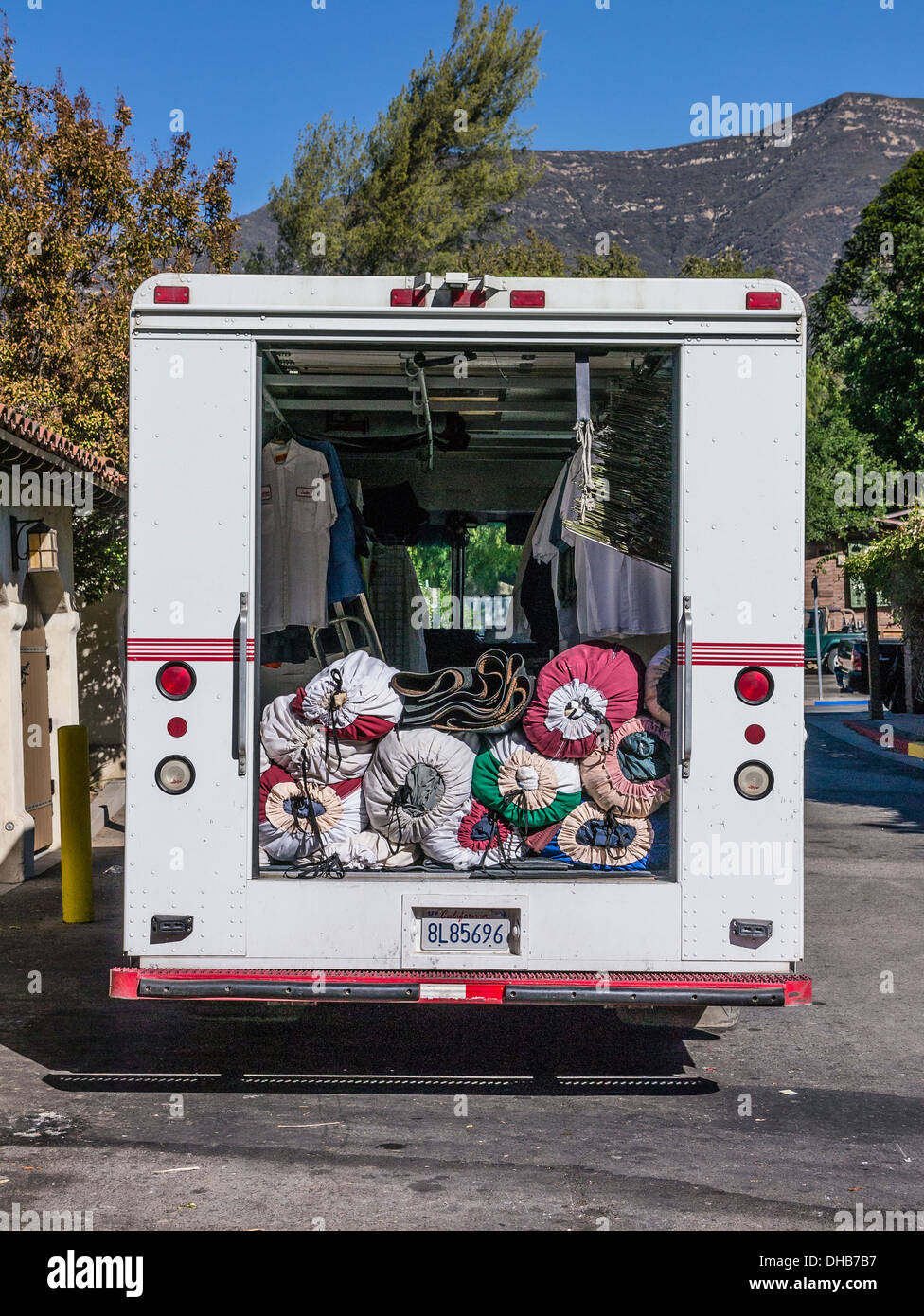 Carichi e fasci di capi di abbigliamento e di biancheria da letto di essere pulito nel retro di un furgone per consegne in Ojai, California. Foto Stock