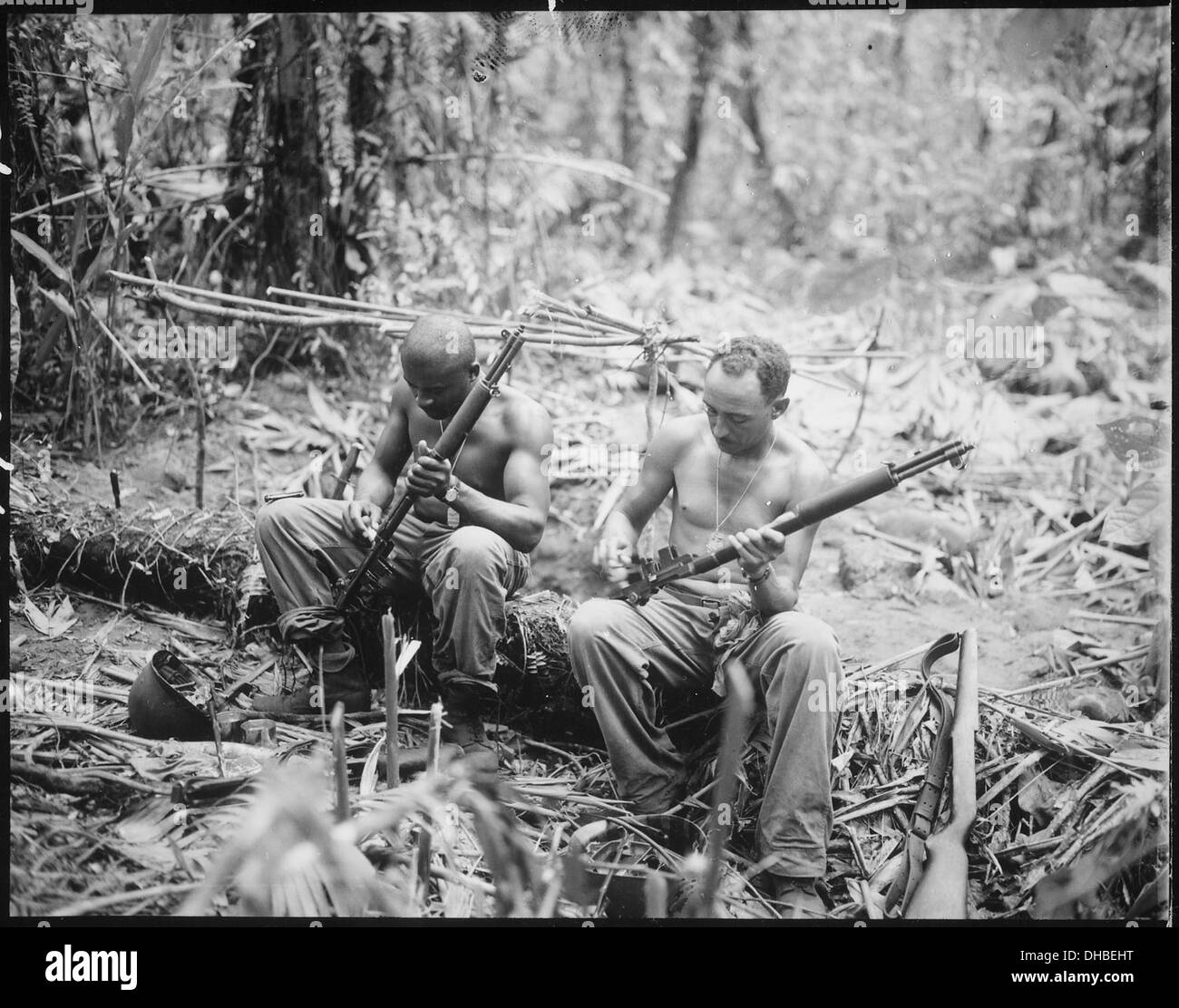 Sergente John C. Clark e S-Sgt. Ford M. Shaw si vede pulire i loro fucili in un'area di bivacco lungo l'Est. Questa immagine cattura un momento di preparazione militare e manutenzione sul campo durante un'operazione. Foto Stock