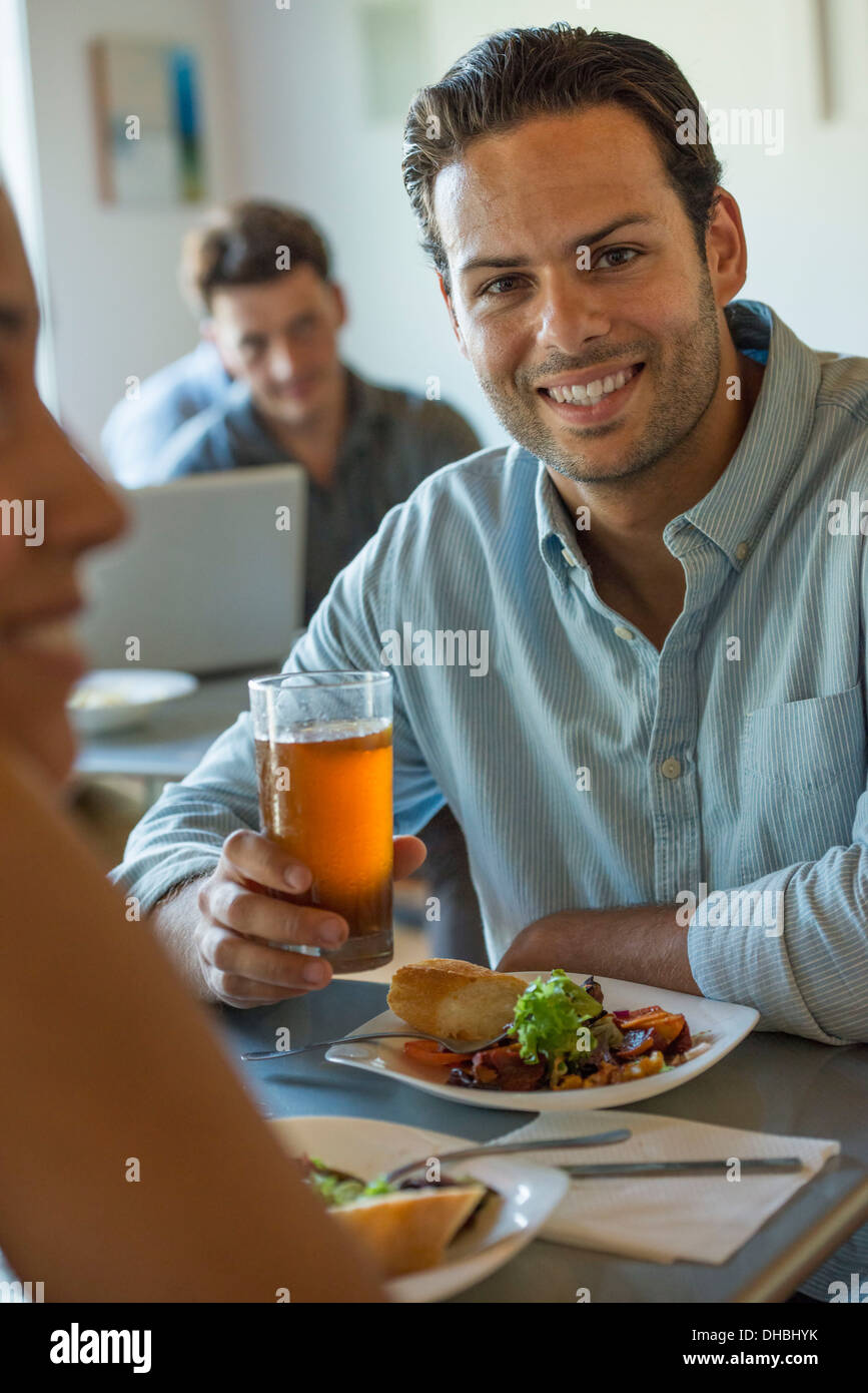 Un gruppo di uomini e donne in un cafe, mangiare e bere e godere della reciproca compagnia. Foto Stock