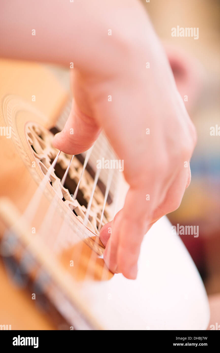 Primo piano della mano womans giocando su legno chitarra acustica Foto Stock