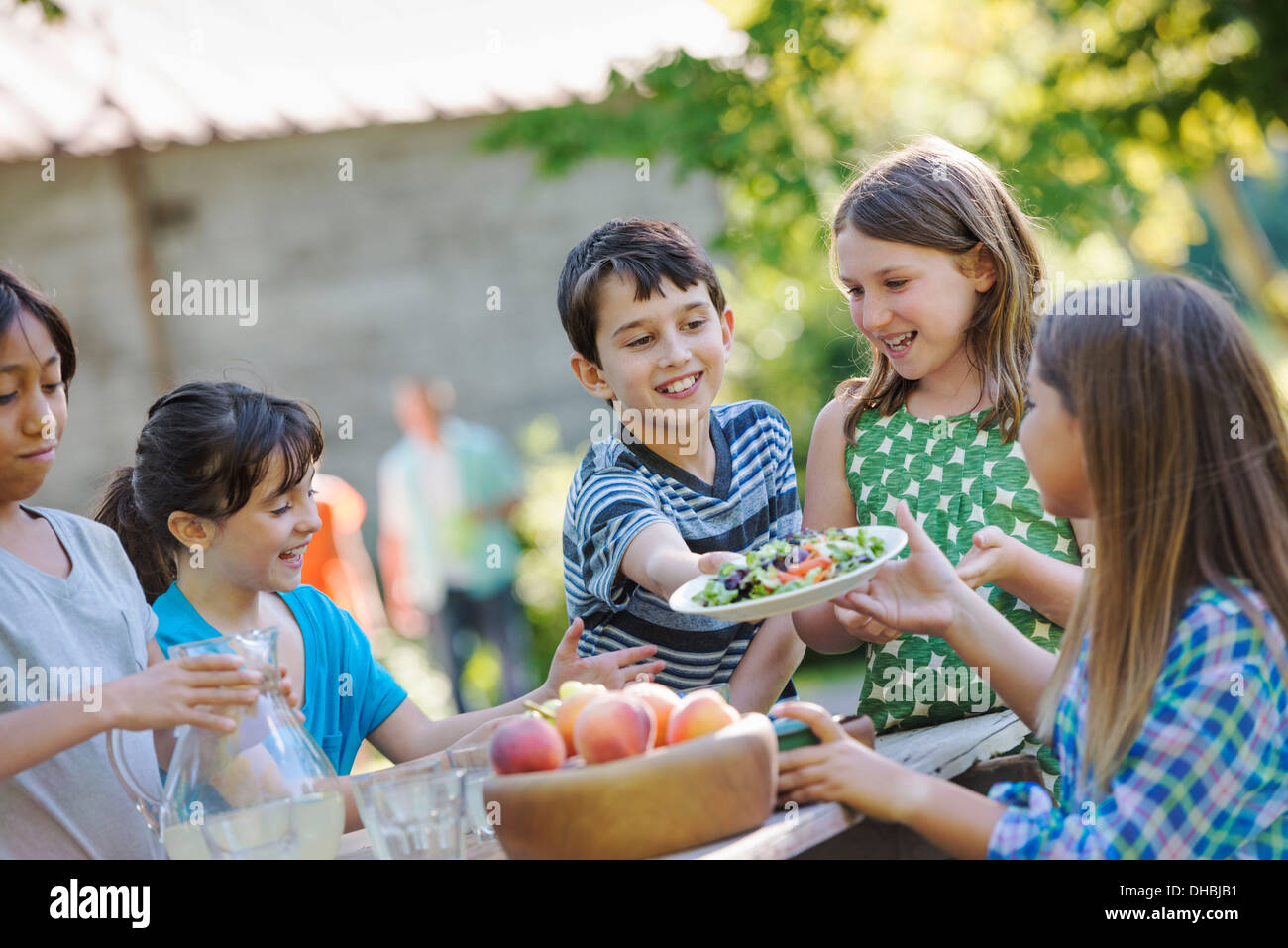 Un gruppo di bambini intorno ad un tavolo per mangiare frutta fresca e insalate. Foto Stock