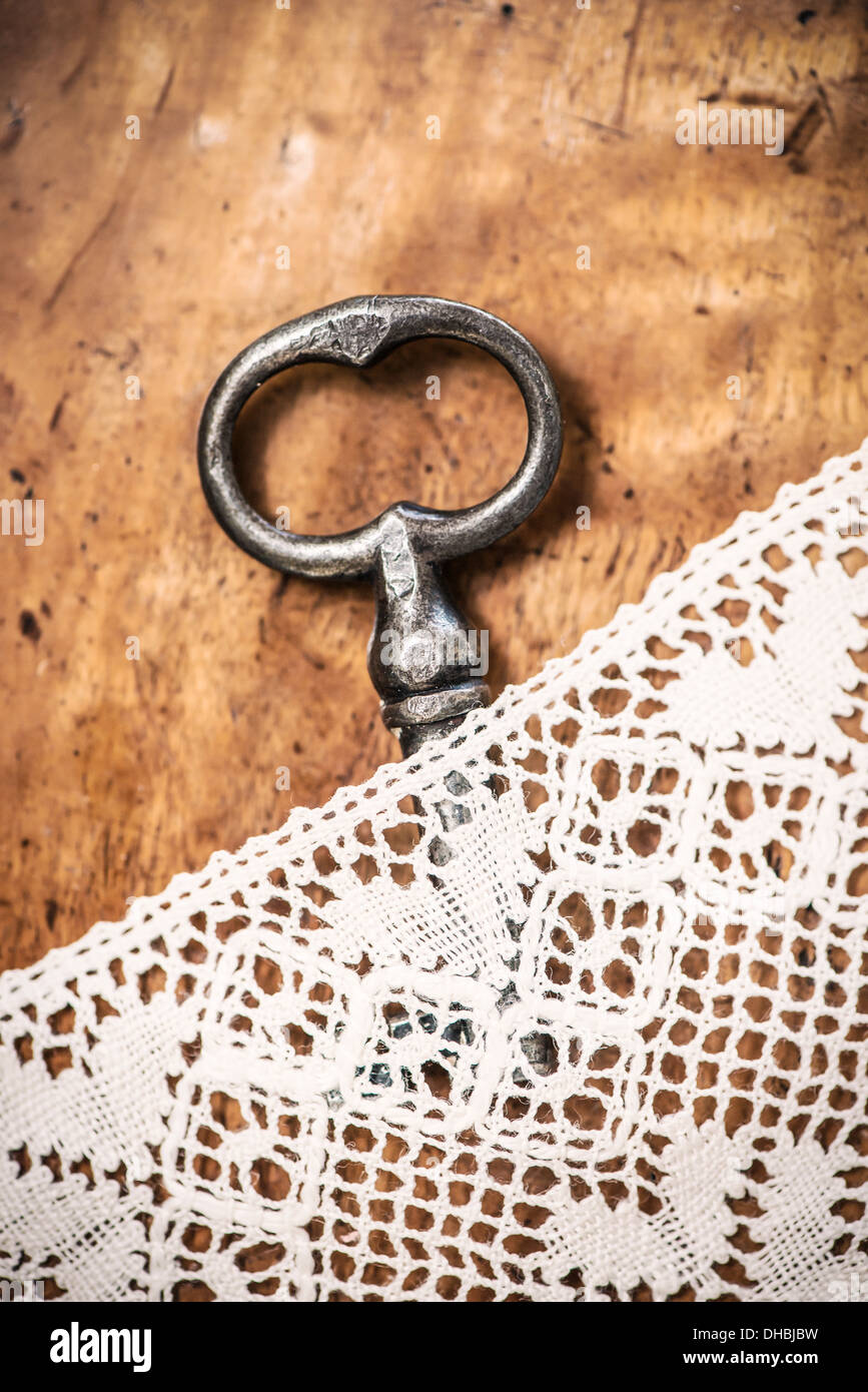 In vecchio stile key giacente su vintage tavolo in legno nascosta sotto la tovaglia di pizzo Foto Stock