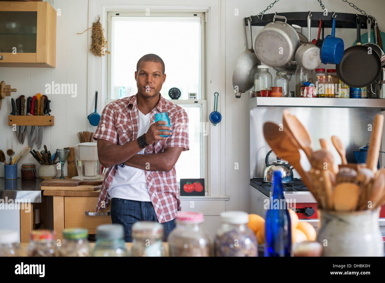 Un uomo con un drink in piedi in un agriturismo cucina. Foto Stock