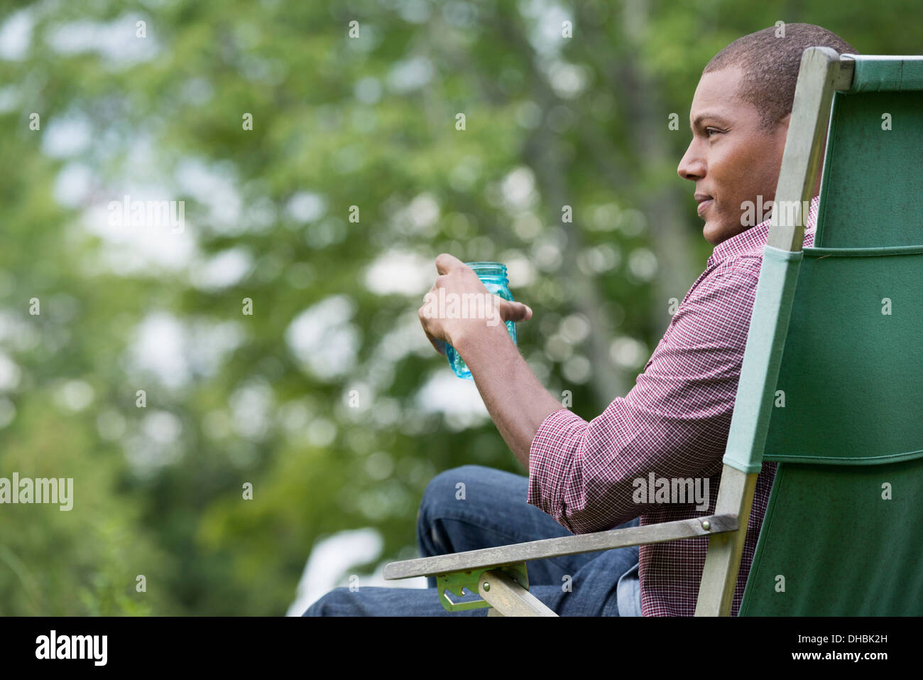 Un uomo seduto in una sedia in un giardino rilassante. Foto Stock