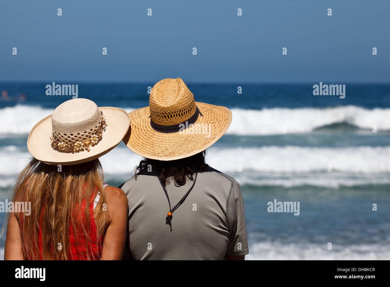 Uomo e donna tan con cappelli di paglia sulla seduta con spalle alla  telecamera guardando il surf in concorrenza LaJolla California Foto stock -  Alamy