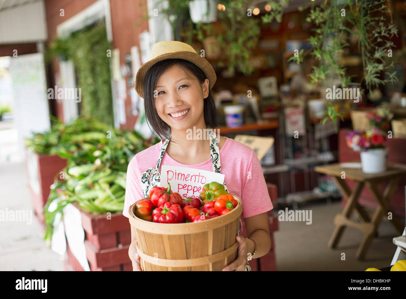Una donna che lavorano su di una azienda agricola biologica di stand, visualizzazione di verdure fresche in vendita. Foto Stock