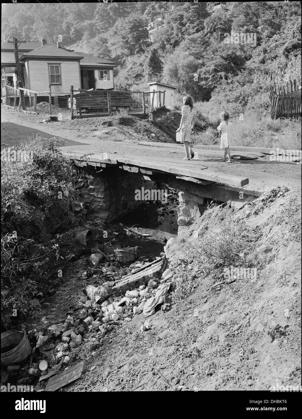 Questa fotografia raffigura le figlie di minatori che trasportano una brocca d'acqua da un idrante vicino a una chiesa alla loro casa su una collina, riflettendo le lotte quotidiane delle comunità minerarie. Foto Stock