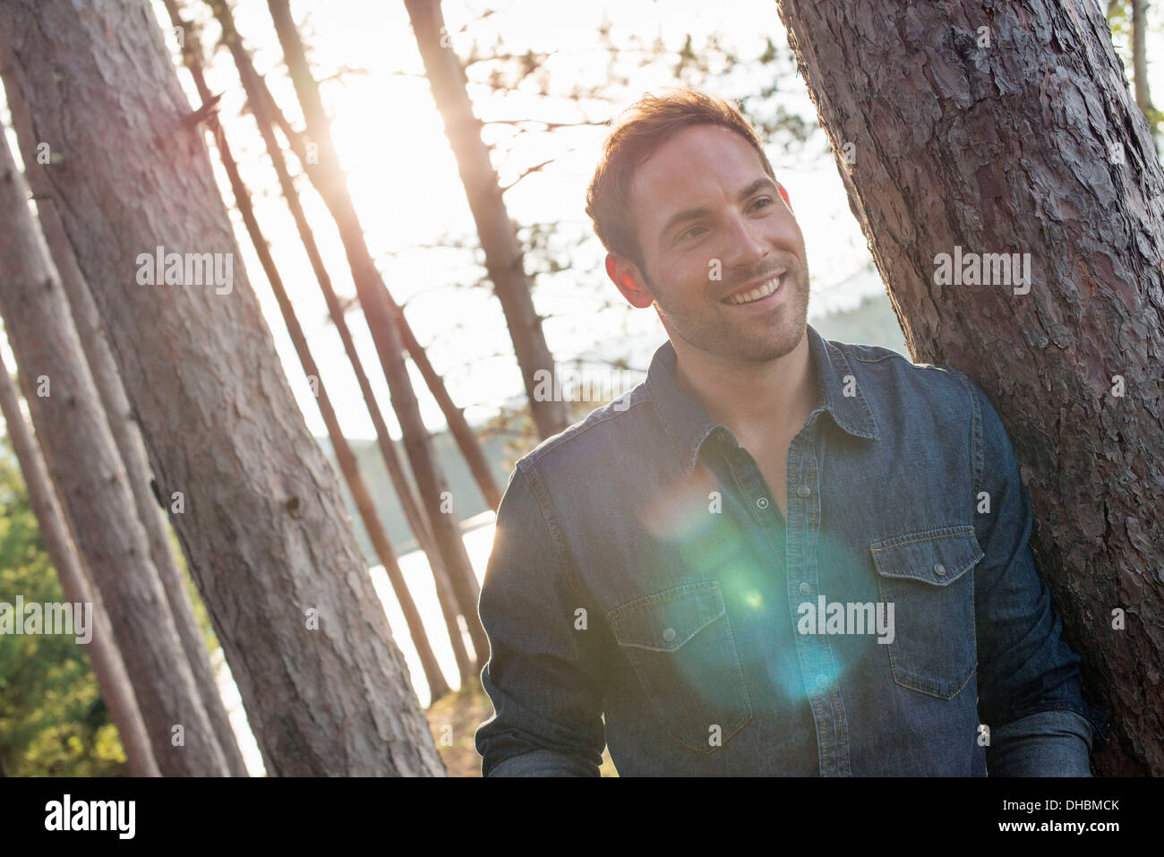 Alberi sulle sponde di un lago. Un uomo sorridente alla fotocamera. Foto Stock