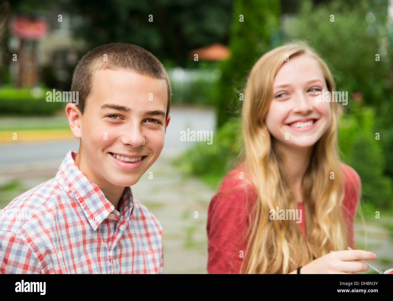 Due giovani, un ragazzo e una ragazza seduta a fianco a fianco di ridere. Foto Stock