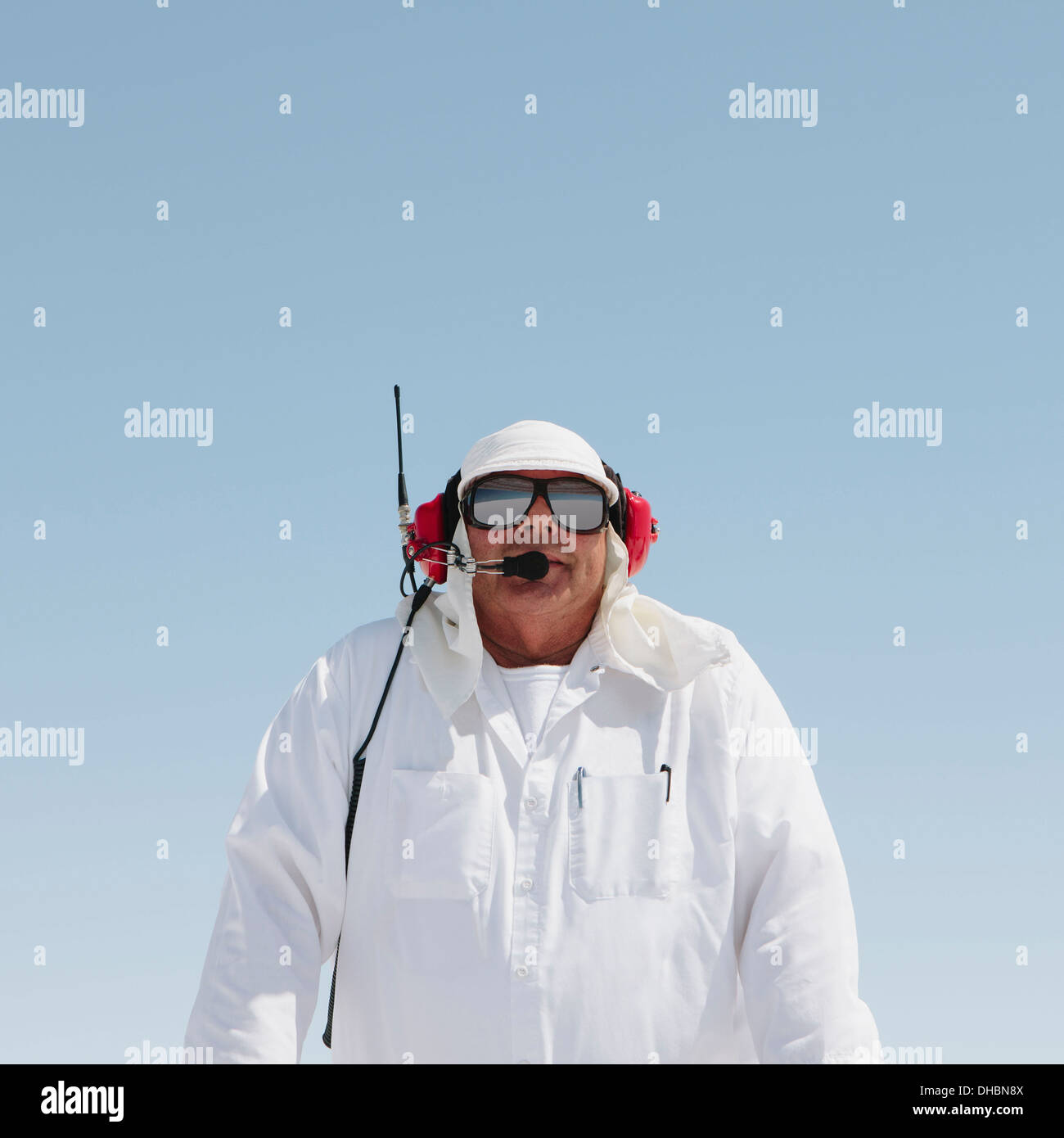 Un uomo in tute bianche, con un auricolare radio, una gara cronometrista ufficiale di un'auto racing event, Speed Week. Foto Stock