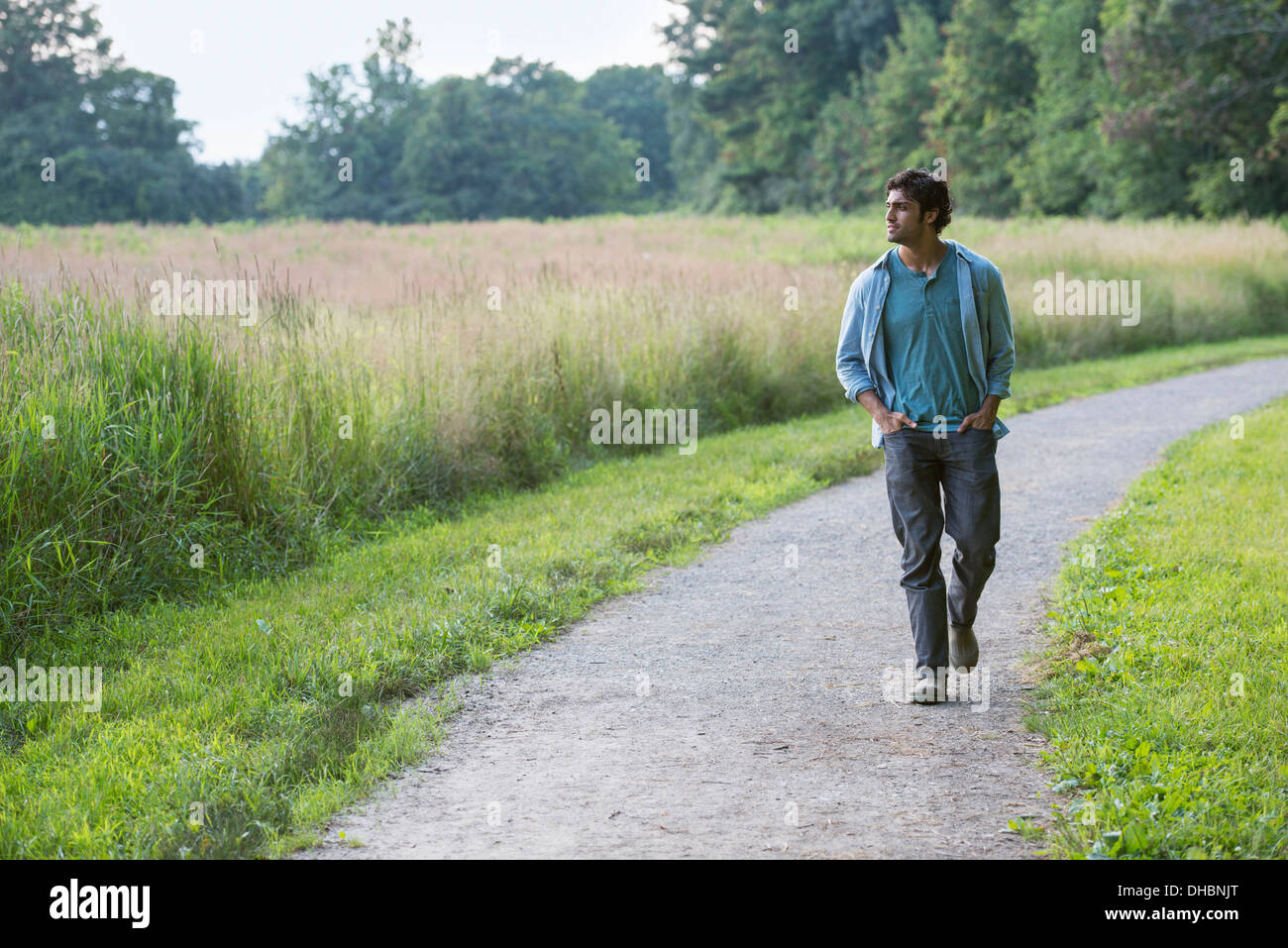 Un giovane uomo che cammina giù per un sentiero con le mani nelle sue tasche. Foto Stock