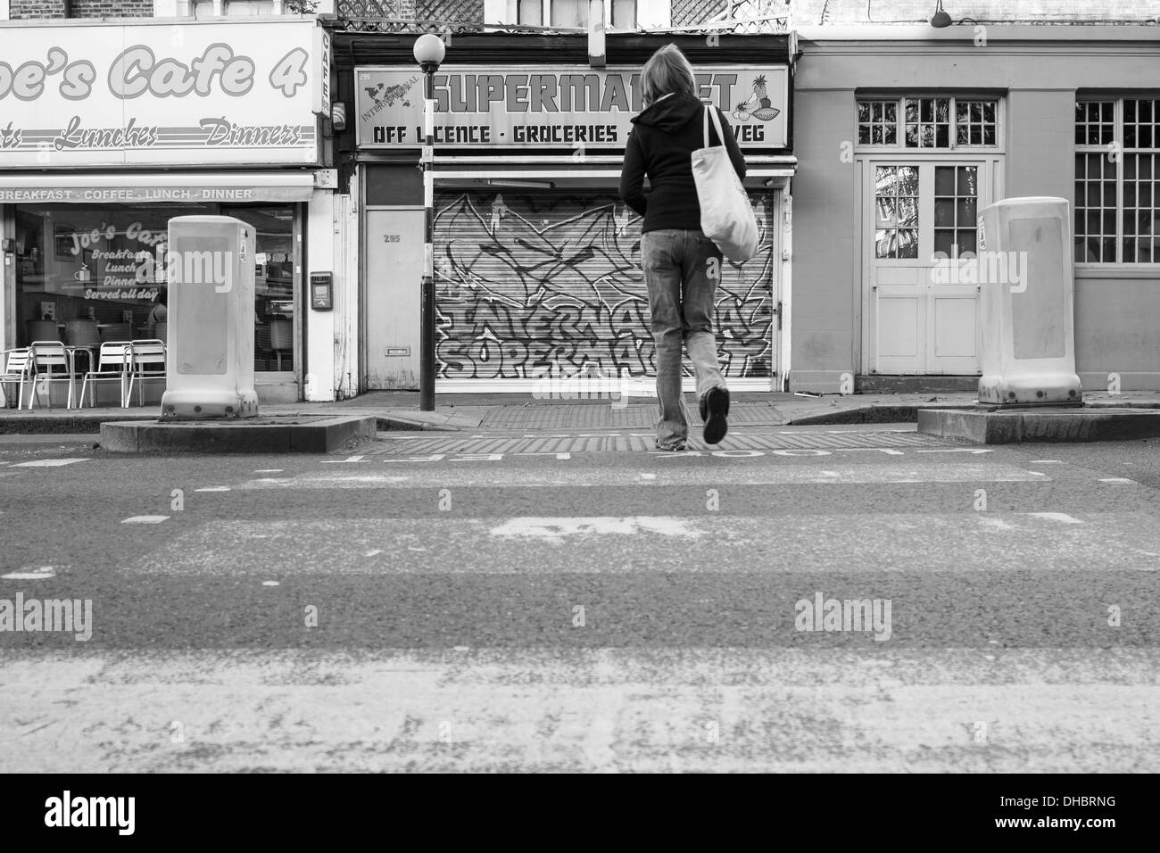 Una donna attraversa un pellicano attraversando il Caledonian Road nel quartiere di Islington a nord di Londra. Foto Stock