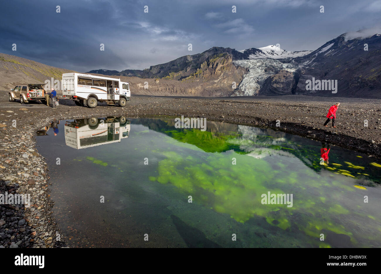 Donna escursionismo da un laghetto con alghe e cenere, Gigjokull ghiacciaio, Icealnd Foto Stock